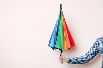 Colorful umbrella in male hand on beige background