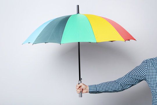 Colorful umbrella in male hand on grey background