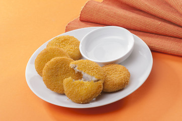 Chicken and cheese fried tikki with lemon and cherry tomato on orange background