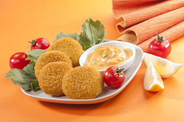 Chicken and cheese fried tikki with lemon and cherry tomato on orange background