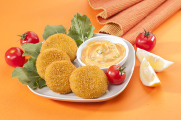 Chicken and cheese fried tikki with lemon and cherry tomato on orange background