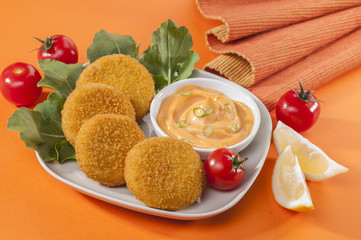 Chicken and cheese fried tikki with lemon and cherry tomato on orange background