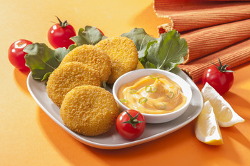 Chicken and cheese fried tikki with lemon and cherry tomato on orange background