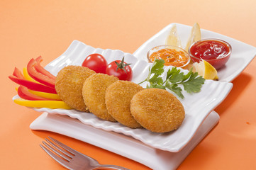 Chicken and cheese fried tikki with lemon and cherry tomato on orange background