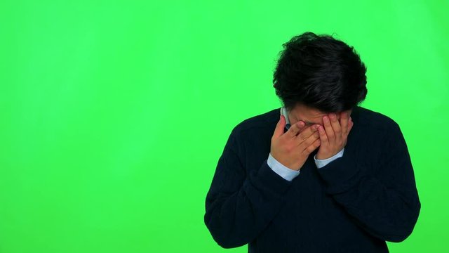 A young Asian man crying - green screen studio