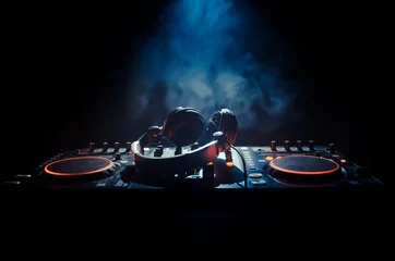  DJ draaien, mixen en krabben in een nachtclub, handen van dj tweaken verschillende trackcontroles op dj& 39 s deck, stroboscooplichten en mist, selectieve focus © zef art