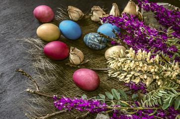 Fototapeta na wymiar Bouquet of wild flowers and colored Easter eggs on a black background