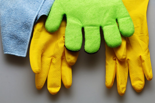 Rubber gloves and cleaning cloths hang on a light background