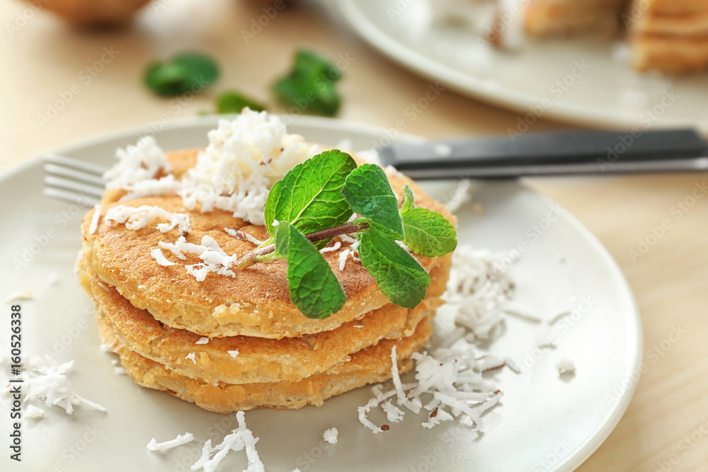 Sticker plate with tasty homemade coconut pancakes and mint on table