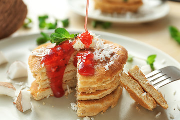 Tasty homemade coconut pancakes with berry sauce on plate