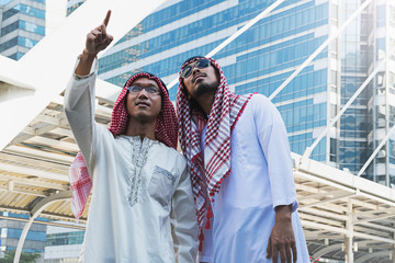 Two Arab businessmen standing by raising both hands up in city, Business good feeling concept