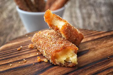 Wooden board with cheese stick on table