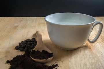 Roasted coffee and white coffee mug on wooden floor.