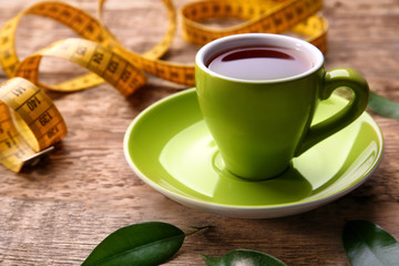 Cup of tea and measuring tape on wooden background