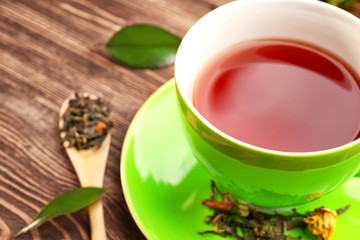 Cup of tea and spoon of brew on wooden background