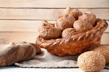 Baked basket with rye buns on wooden background