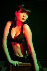 Aggressive woman wearing lingerie in red and green light. Studio photo. Hot brunette wearing suspenders