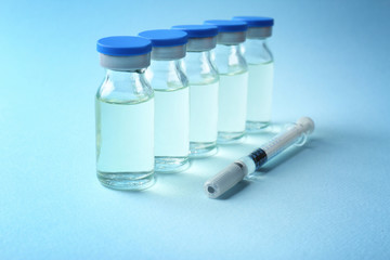 Vaccine in vials with syringe on color background