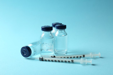Vaccine in vials with syringes on color background