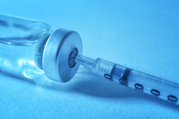 Vaccine in vial with syringe on color background