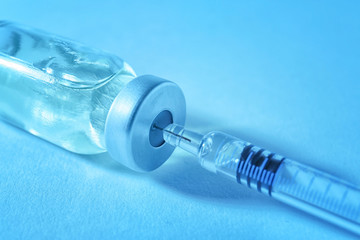 Vaccine in vial with syringe on color background