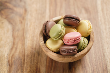 assorted macarons in wood bowl on wooden table