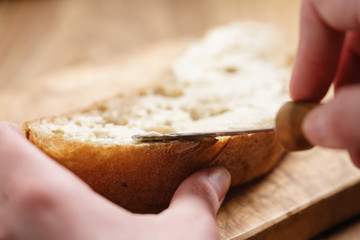 young female hands spreading butter on bread