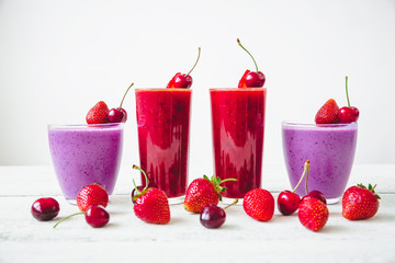 Cherry, blueberry and strawberry smoothie and tasty berries on white table. Natural milkshake