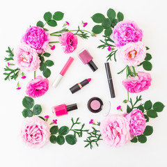 Obraz na płótnie Canvas Beauty blogger desk with cosmetics - lipstick, eye shadows, nail polish and pink frame of flowers on white background. Flat lay, top view.