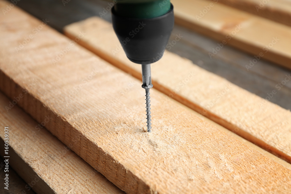 Wall mural Driving screw nail into wooden board in carpenter's workshop, closeup