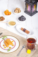 Obraz na płótnie Canvas Collection of Oriental Sweets ( Balah El Sham - Dried Fruits ) and glass of tea with Ramadan Lantern