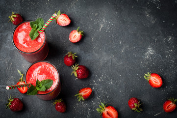 Strawberry smoothie in glass on dark background with copy space. Summer drink cocktail. Healthy eating dieting and breakfast concept. Top view