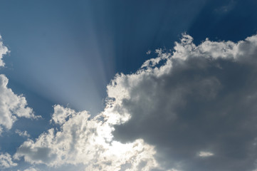 Rays from the sun breaking trhough the dark storm clouds filling the blue sky