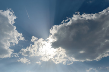 Sun casting god light rays at the camera faning out in all directions from behind the dark clouds