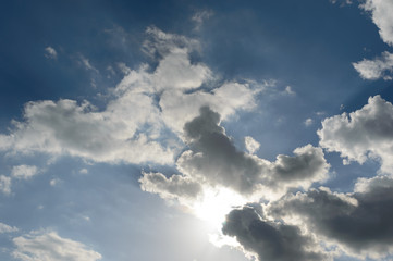 Sun light breaking through dark storm cloud formations taking a bleu sky