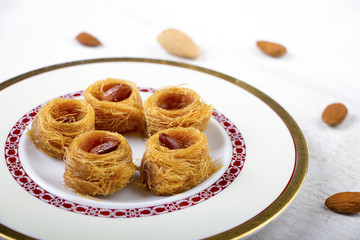 Obraz na płótnie Canvas Oriental Sweets - kunafa in a plate on white wood background