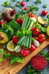 Seasonal vegetables ingredient for salad, red radish, tomatoes, spring onions, beetroot, lemons and avocado on oak cutting board with sea salt and corn peppers