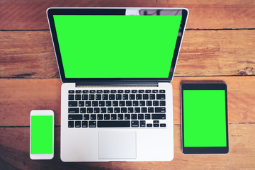 Mockup image of mobile phone , laptop and tablet pc with blank green screen on vintage wood table...