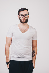 unshaved man in white t-shirt with tattoo wearing big modern glasses