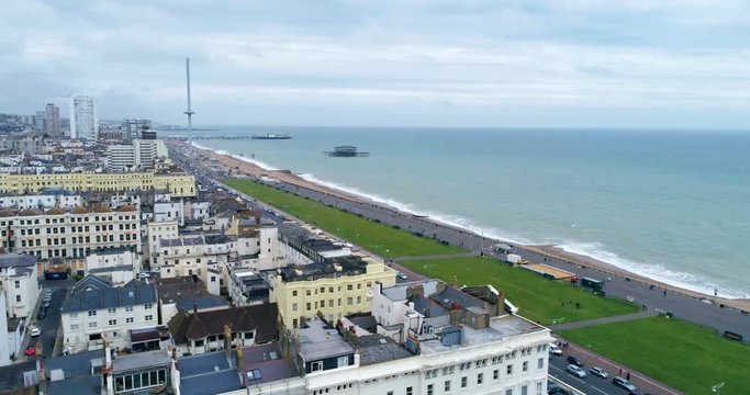 Aerial dolly view of the town of Brighton and Hove towards the beach and the two piers