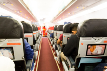 Defocused airplane cabin interior with seats and passengers
