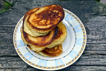 домашние печёные оладьи на белой тарелке на серой доске