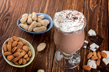 Homemade milkshake ( smoothie) with nuts and chocolate pieces on rustic wooden table