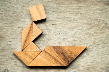 Tangram puzzle in man sail the boat shape on wooden background