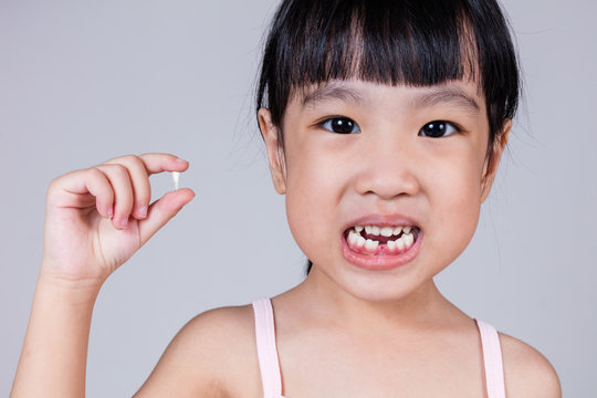 Asian Chinese little girl holding her missing tooth