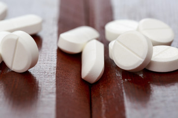 Various white pills on wooden table