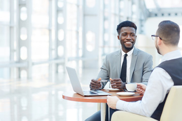 Fototapeta na wymiar Portrait of successful African-American businessman smiling during meeting with colleague at coffee break