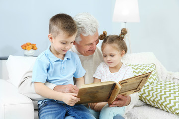 Grandfather looking at photo album with his grandchildren