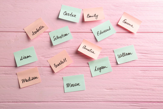 Paper stickers with different names on wooden background. Concept of choosing baby name