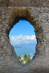 A hole in the wall of the Grotto di Catullo with a view of Lake Garda